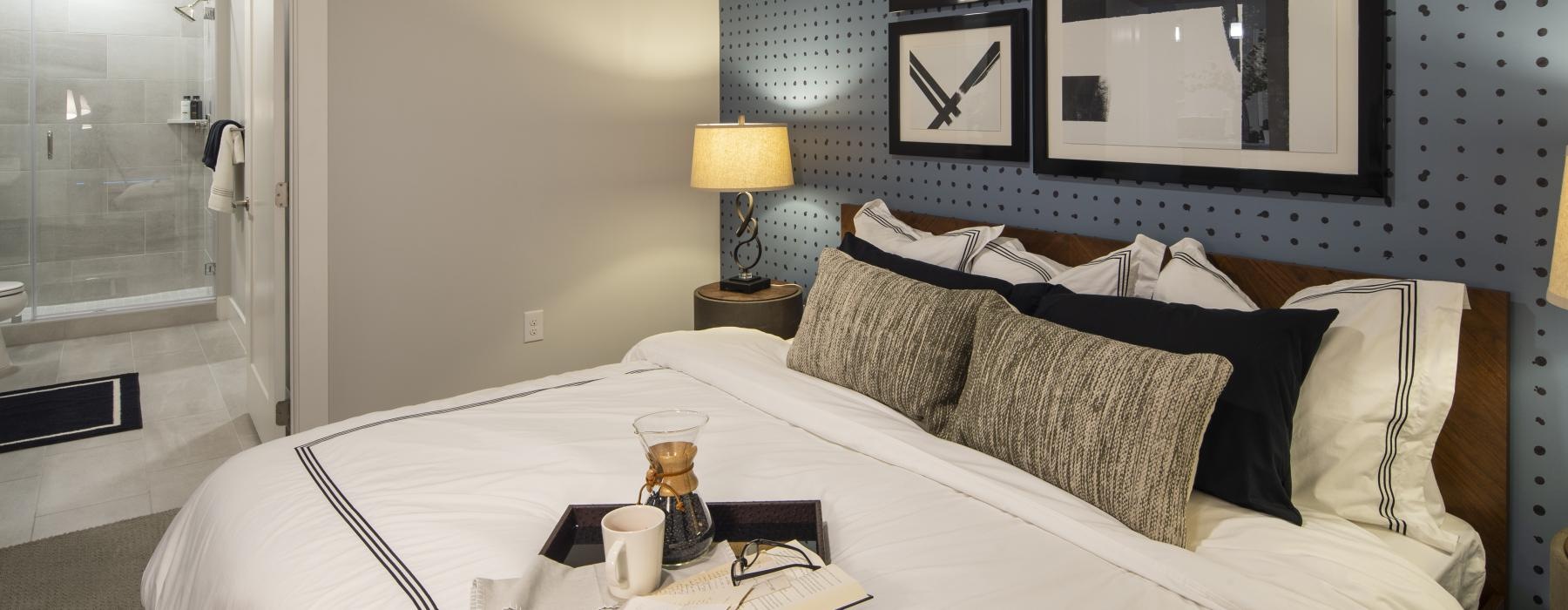 a bed with pictures above it and end table with a lamp